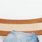 Furniture Choice - Stack of blue jeans of different shades on modern wooden chair against white wall